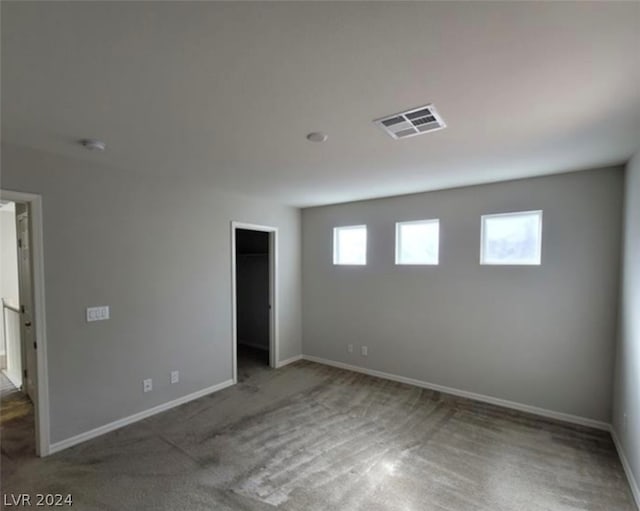 unfurnished bedroom featuring carpet, multiple windows, and a walk in closet