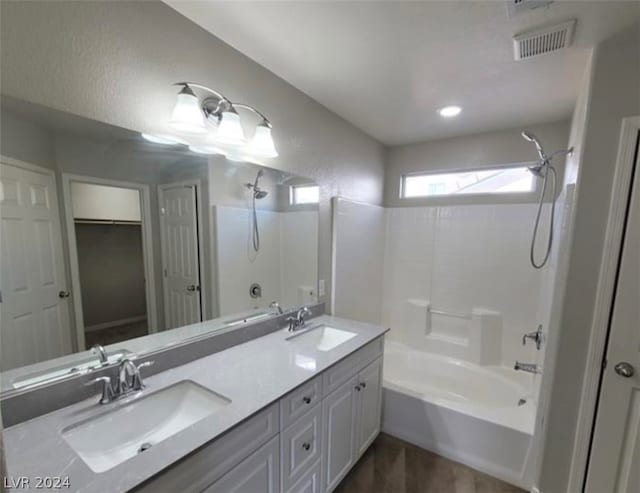 bathroom featuring large vanity, double sink, and shower / bathing tub combination