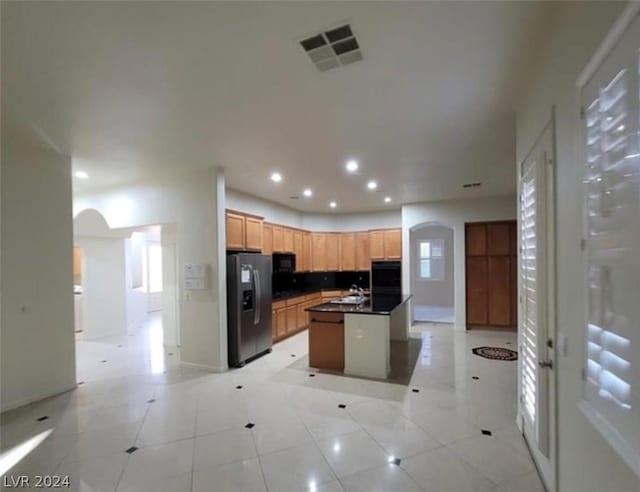 kitchen featuring sink, a kitchen island with sink, stainless steel fridge with ice dispenser, and light tile patterned floors