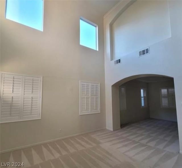 unfurnished living room featuring a towering ceiling and carpet floors