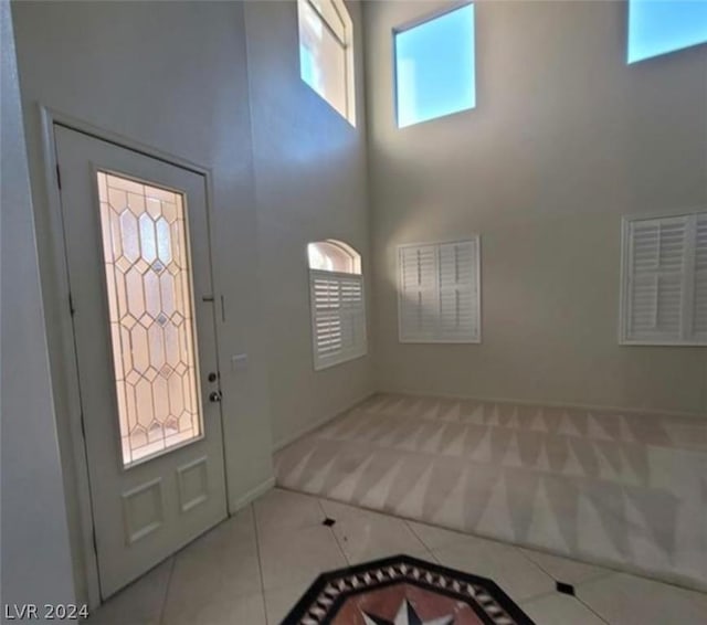 entryway with light tile patterned flooring and a high ceiling