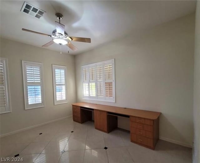 unfurnished office with light tile patterned flooring, built in desk, and ceiling fan