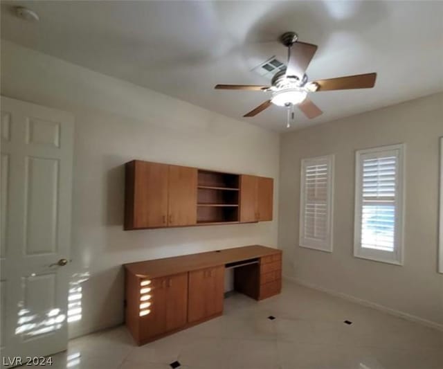 unfurnished office featuring ceiling fan and built in desk