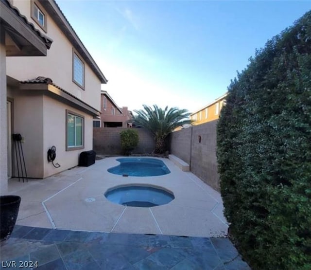 view of swimming pool featuring an in ground hot tub and a patio area