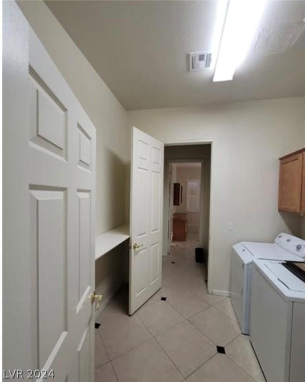 washroom featuring light tile patterned floors, washing machine and dryer, and cabinets