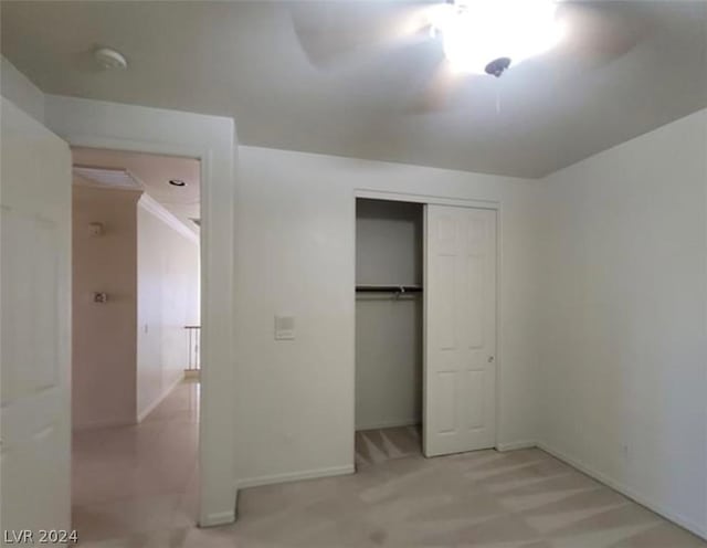 unfurnished bedroom featuring light colored carpet, ceiling fan, and a closet