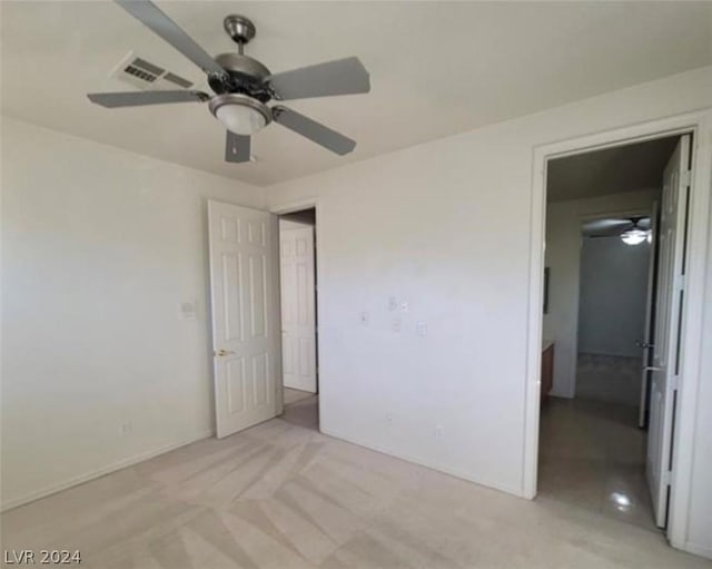 unfurnished bedroom with light carpet, a spacious closet, and ceiling fan