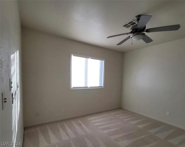 spare room featuring light colored carpet and ceiling fan