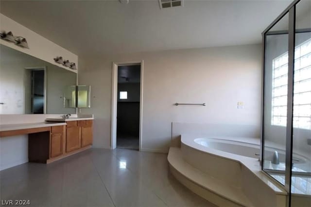 bathroom featuring vanity, a relaxing tiled tub, and tile patterned floors