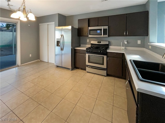 kitchen featuring sink, light tile patterned flooring, stainless steel appliances, pendant lighting, and an inviting chandelier