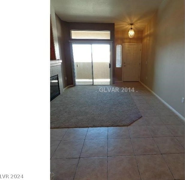 tiled foyer entrance featuring a glass covered fireplace and baseboards