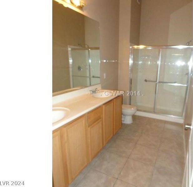 bathroom with walk in shower, double sink, tile floors, oversized vanity, and toilet