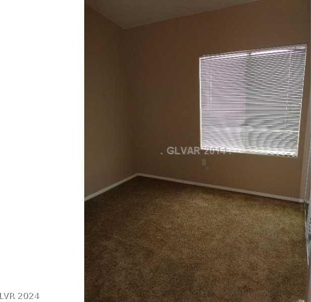 empty room featuring dark colored carpet and baseboards