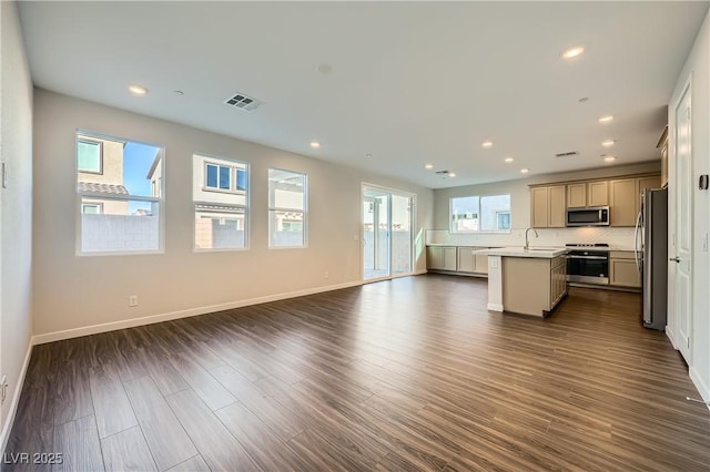 kitchen with sink, appliances with stainless steel finishes, an island with sink, a wealth of natural light, and dark wood-type flooring