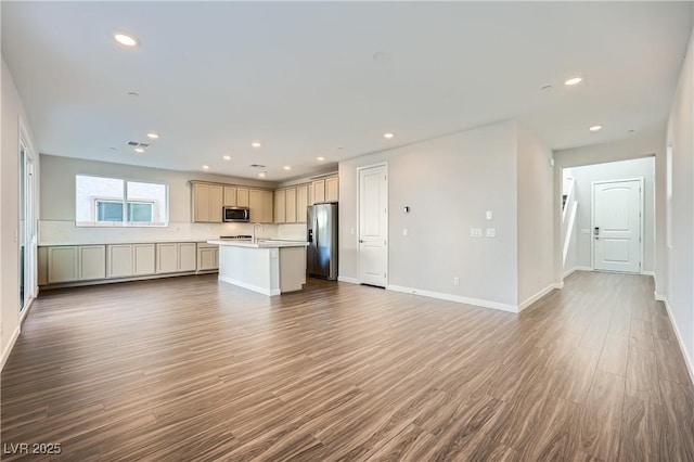 kitchen with sink, appliances with stainless steel finishes, tasteful backsplash, a center island with sink, and dark wood-type flooring