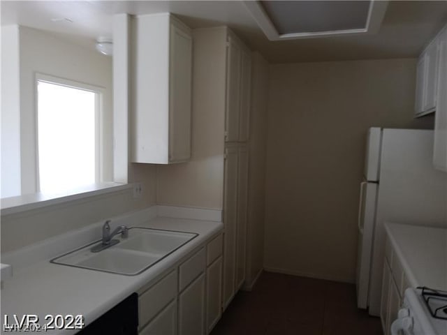 kitchen featuring white cabinetry, sink, stove, and white fridge