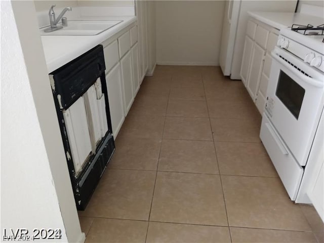 kitchen featuring dishwasher, white gas range, sink, white cabinets, and light tile patterned floors