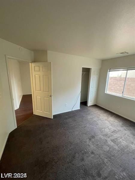 unfurnished bedroom featuring a closet and dark colored carpet