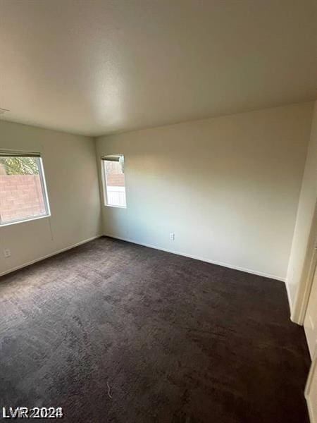 unfurnished room featuring dark carpet