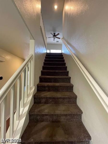 stairway featuring ceiling fan