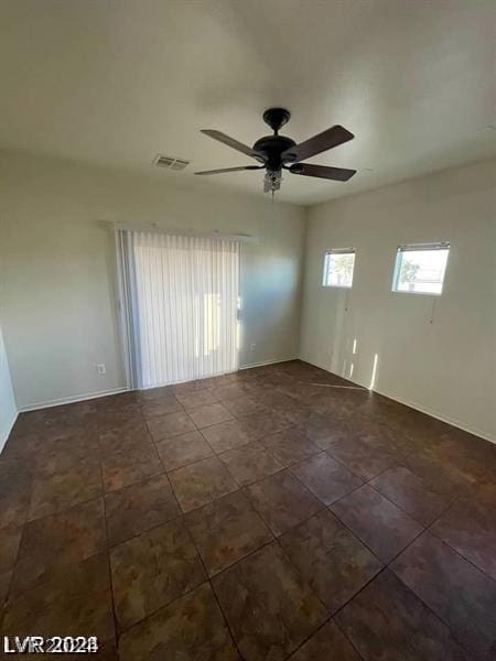 spare room featuring ceiling fan and dark tile patterned flooring