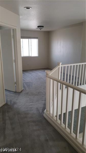 hall with dark colored carpet