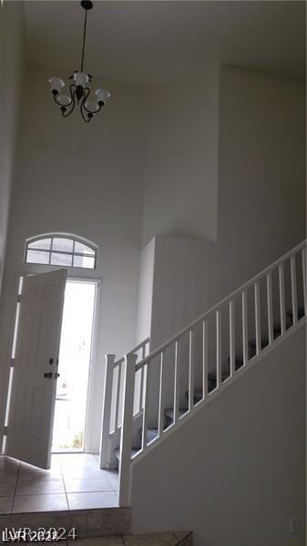 tiled entrance foyer featuring a high ceiling and a notable chandelier