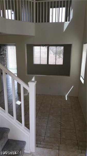 staircase with tile patterned flooring and a high ceiling