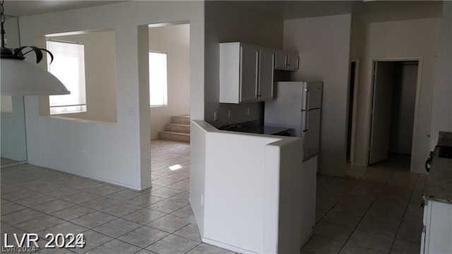 kitchen with white cabinetry, light tile patterned flooring, and white fridge