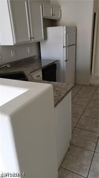 kitchen with white cabinetry, light tile patterned floors, sink, and white refrigerator