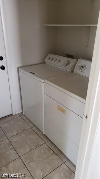 clothes washing area featuring washer and clothes dryer and light tile patterned floors