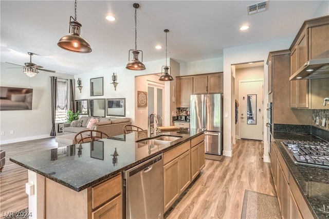 kitchen with decorative light fixtures, tasteful backsplash, sink, stainless steel appliances, and a spacious island