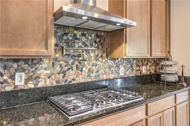 kitchen featuring backsplash, stainless steel gas stovetop, extractor fan, and dark stone counters