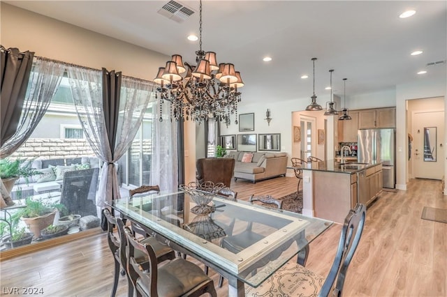 dining room with an inviting chandelier, sink, and light hardwood / wood-style floors