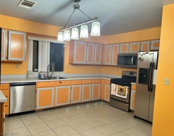 kitchen featuring stainless steel appliances, sink, light tile patterned floors, and decorative light fixtures