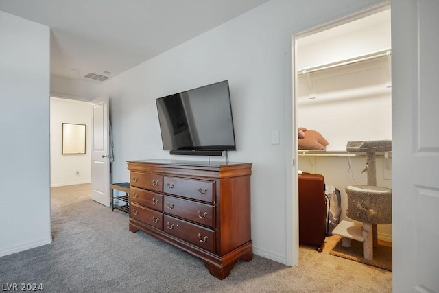 bedroom featuring a walk in closet, light colored carpet, and a closet