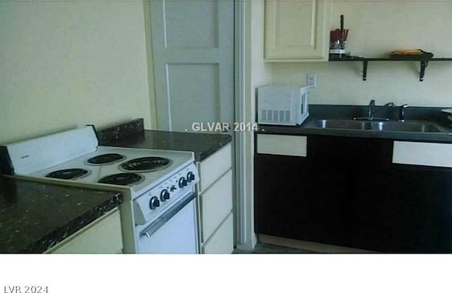 kitchen featuring white cabinetry, dark stone counters, white electric range oven, and sink