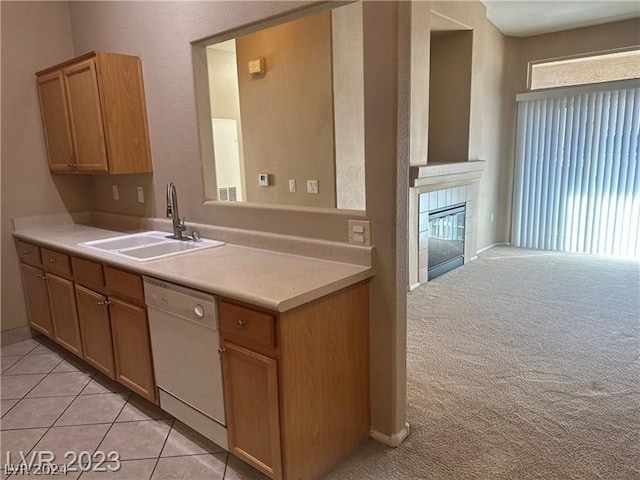 kitchen with sink, dishwasher, a fireplace, and light tile floors