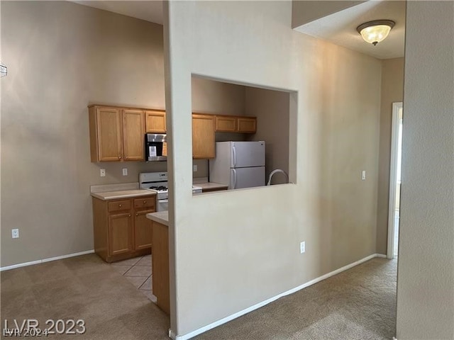 kitchen with light carpet, white fridge, and range with gas cooktop