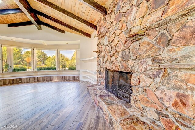 unfurnished living room with high vaulted ceiling, a stone fireplace, beamed ceiling, hardwood / wood-style flooring, and wood ceiling