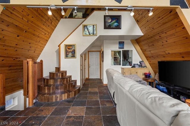 living room with high vaulted ceiling, track lighting, and wood walls