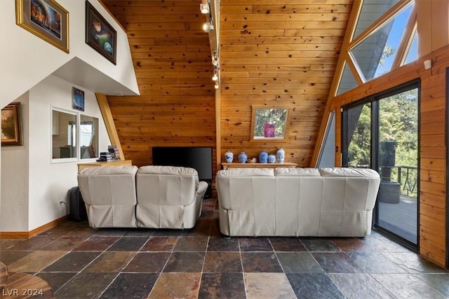 living room featuring high vaulted ceiling and wood walls