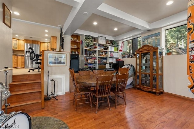 dining room with light hardwood / wood-style flooring and beamed ceiling