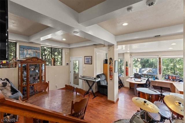 dining space with light wood-type flooring and beamed ceiling