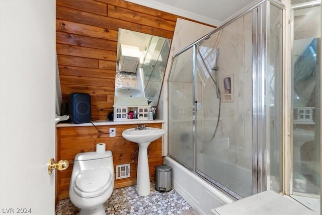 bathroom with bath / shower combo with glass door, wood walls, and toilet