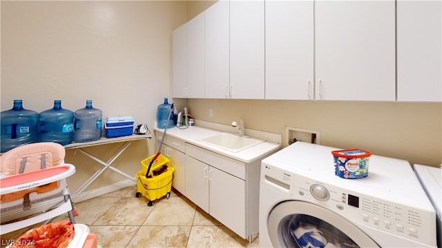 washroom featuring cabinets, sink, light tile patterned floors, and washing machine and clothes dryer