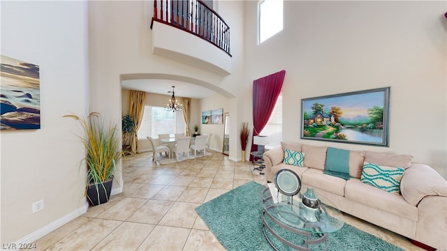 living room with tile patterned flooring, a towering ceiling, and a chandelier