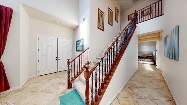 stairway with tile patterned flooring and a high ceiling