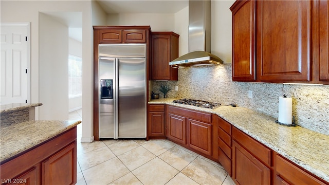 kitchen with stainless steel appliances, tasteful backsplash, light stone countertops, and wall chimney range hood