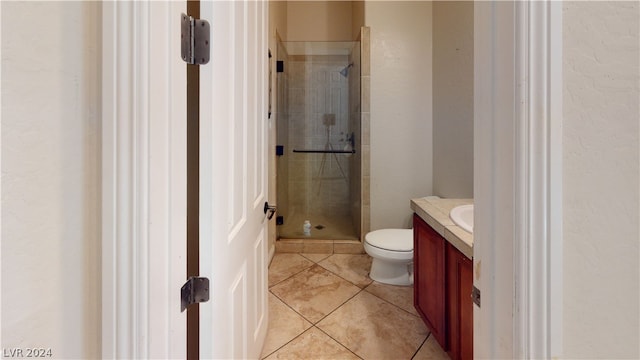 bathroom featuring tile patterned flooring, vanity, toilet, and walk in shower